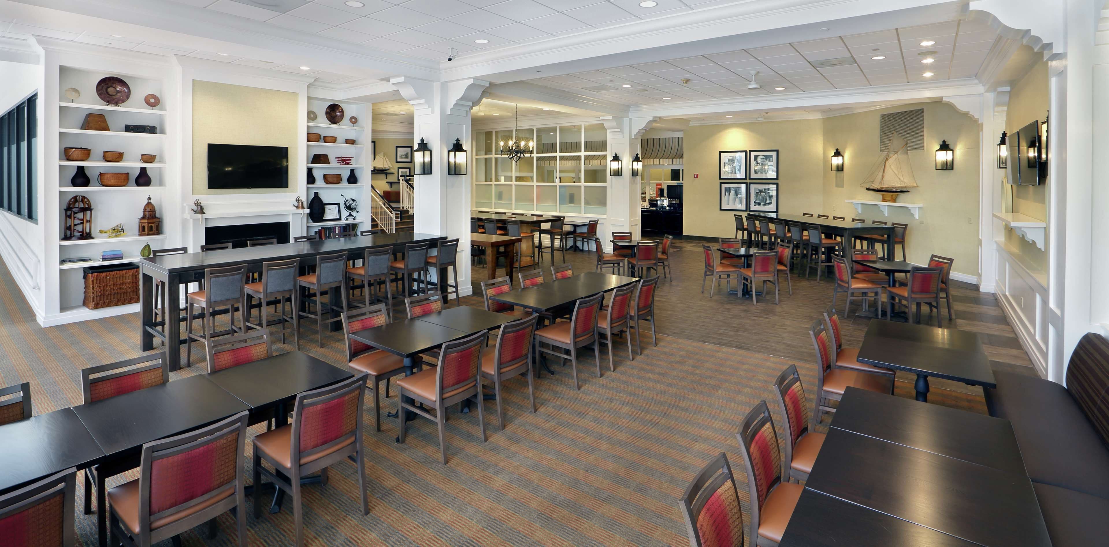 A spacious dining area with multiple tables and chairs, a bar area, and a variety of decorative items on shelves.