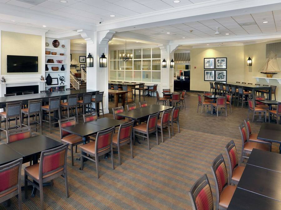 A spacious dining area with multiple tables and chairs, a bar area, and a variety of decorative items on shelves.