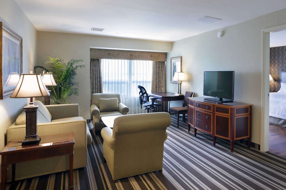 A hotel room with a bed, a TV, a desk, and a seating area with chairs and a sofa.