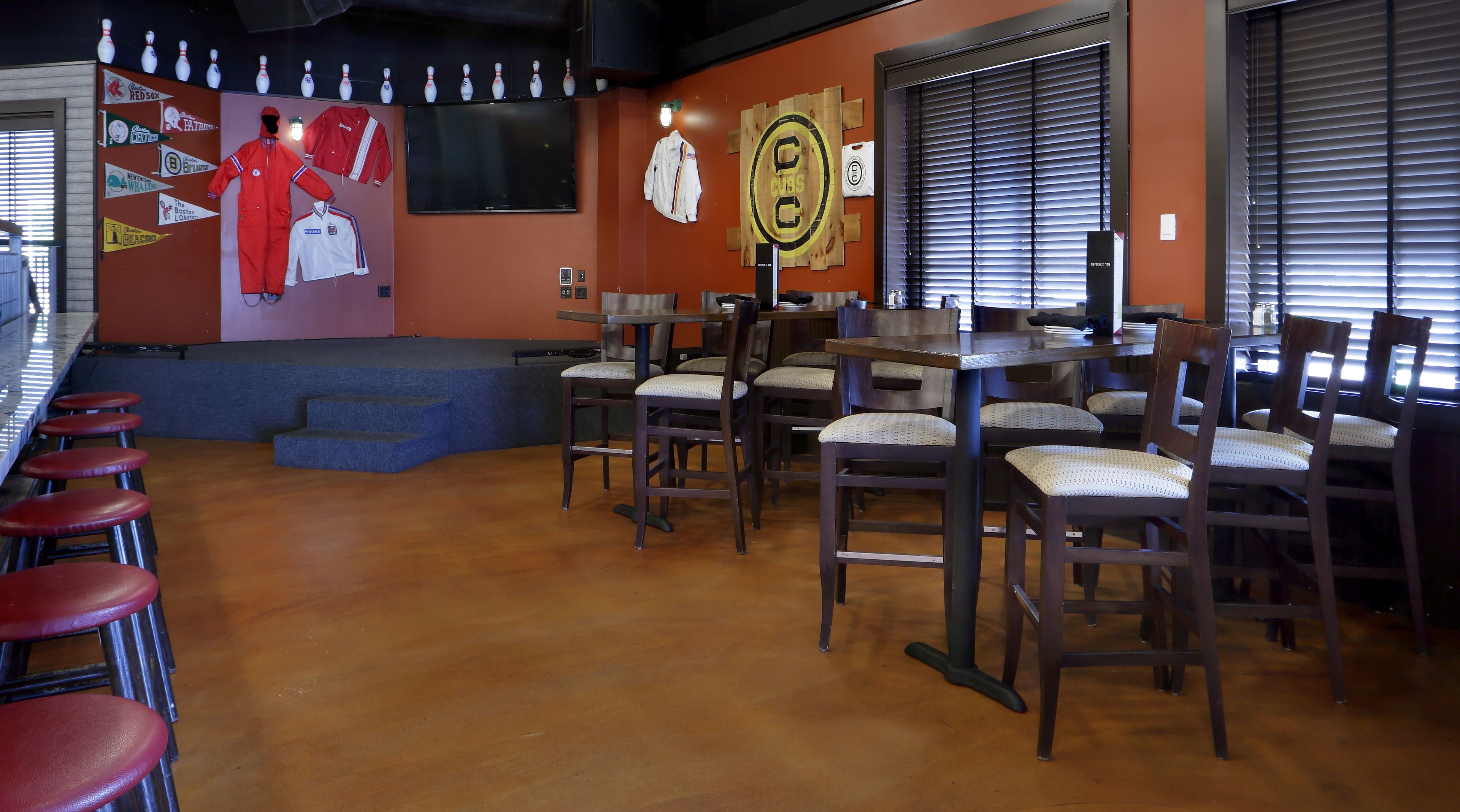 A bowling alley with multiple lanes, a bar area with stools, and a seating area with tables and chairs.