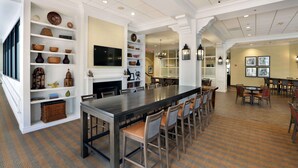 Una cocina amplia con una isla grande, taburetes de bar y estantes con utensilios de cocina.