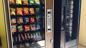 Una máquina expendedora con diferentes opciones de snacks y un dispensador de bebidas aparte.