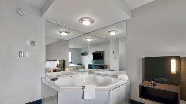 A modern bathroom with a large freestanding bathtub, a mirror, and a built-in TV.