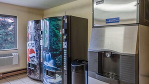 A room with a refrigerator, a water dispenser, and a trash can.