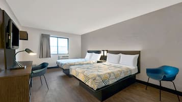 A hotel room with two beds, a desk, a chair, a TV, and a window with curtains.