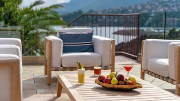 Una terraza con mobiliario exterior, una cesta de frutas y bebidas.