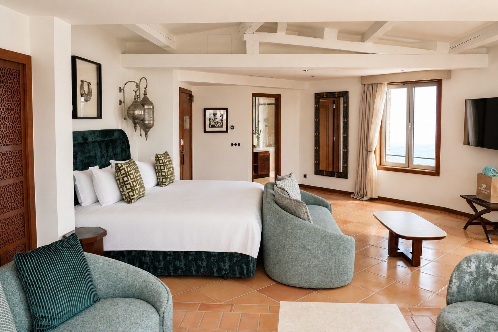 A spacious bedroom with a large bed, two sofas, a TV, and a view of the sea.