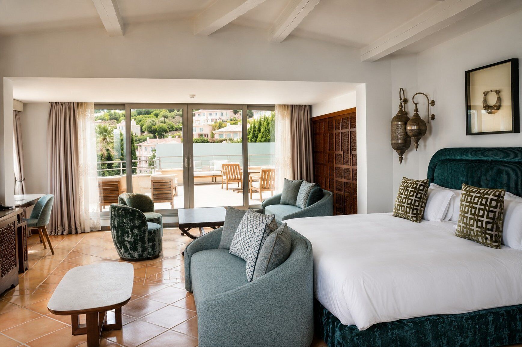 Habitación de hotel con cama, dos sofás, una mesita y un balcón con mobiliario de exterior.