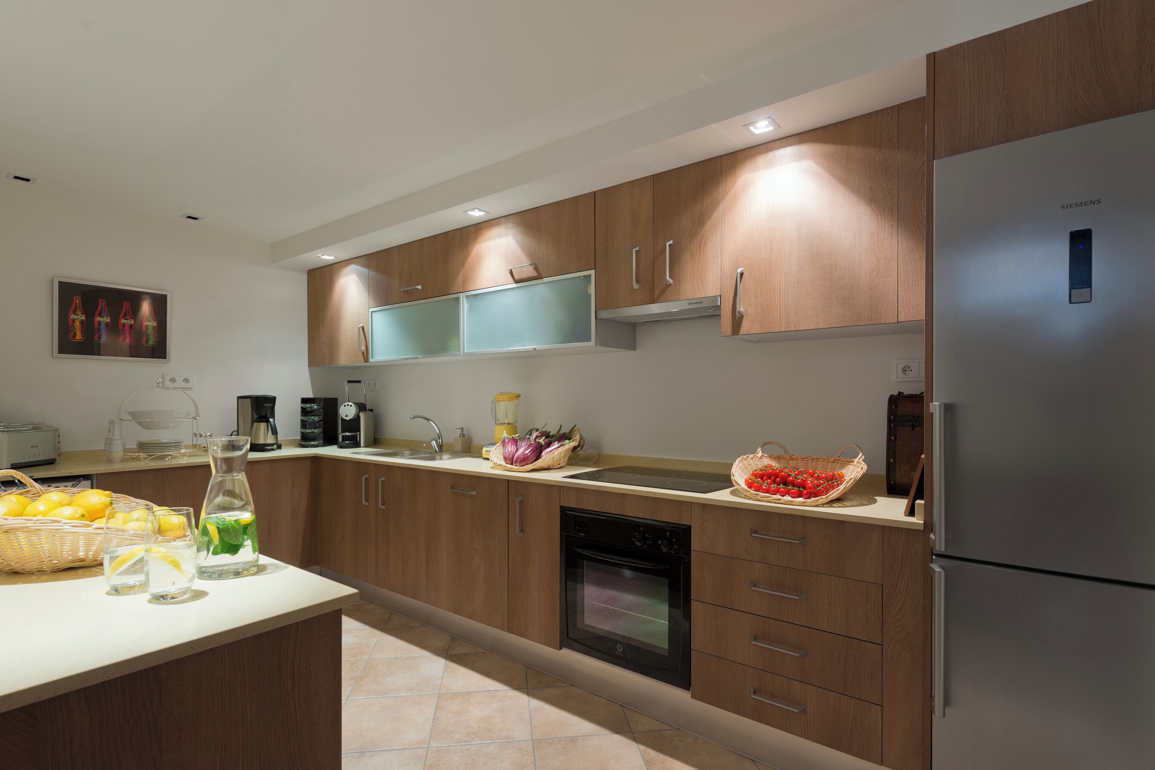 Una cocina moderna con armarios de madera, horno empotrado y refrigerador de acero inoxidable.
