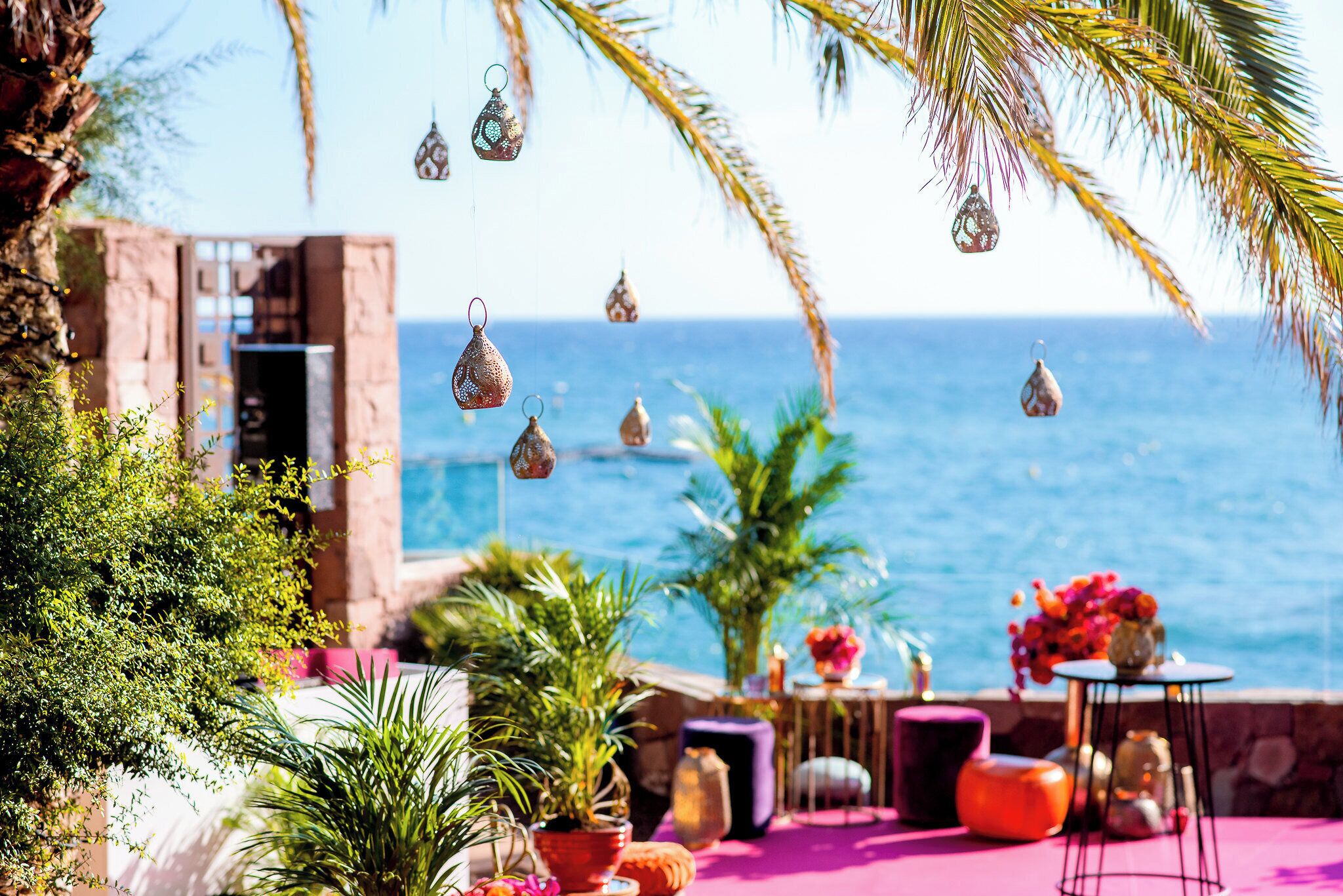 A coastal outdoor seating area with plants, a table, and hanging decorations.