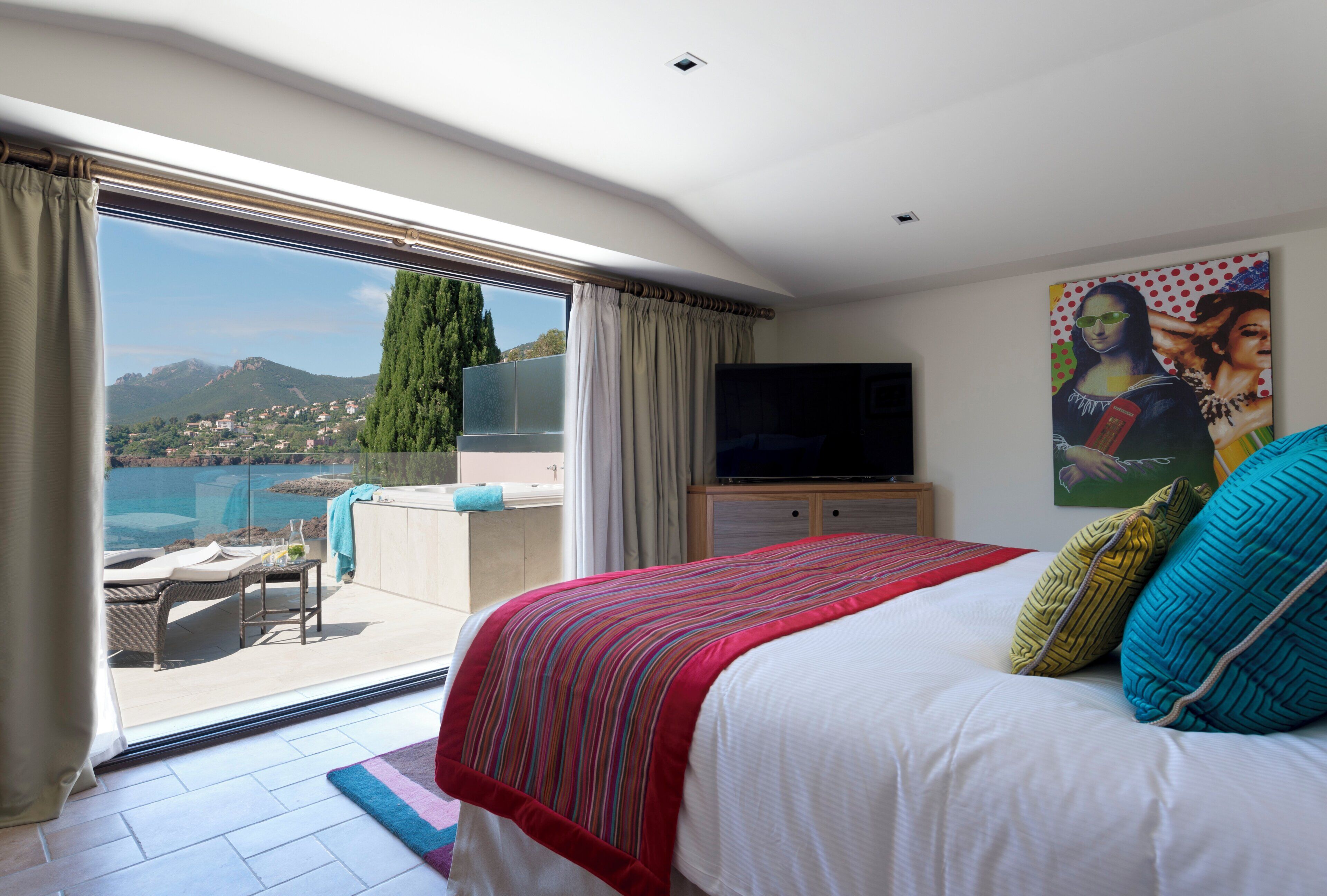 Un dormitorio con una cama grande, televisión y vistas al mar.