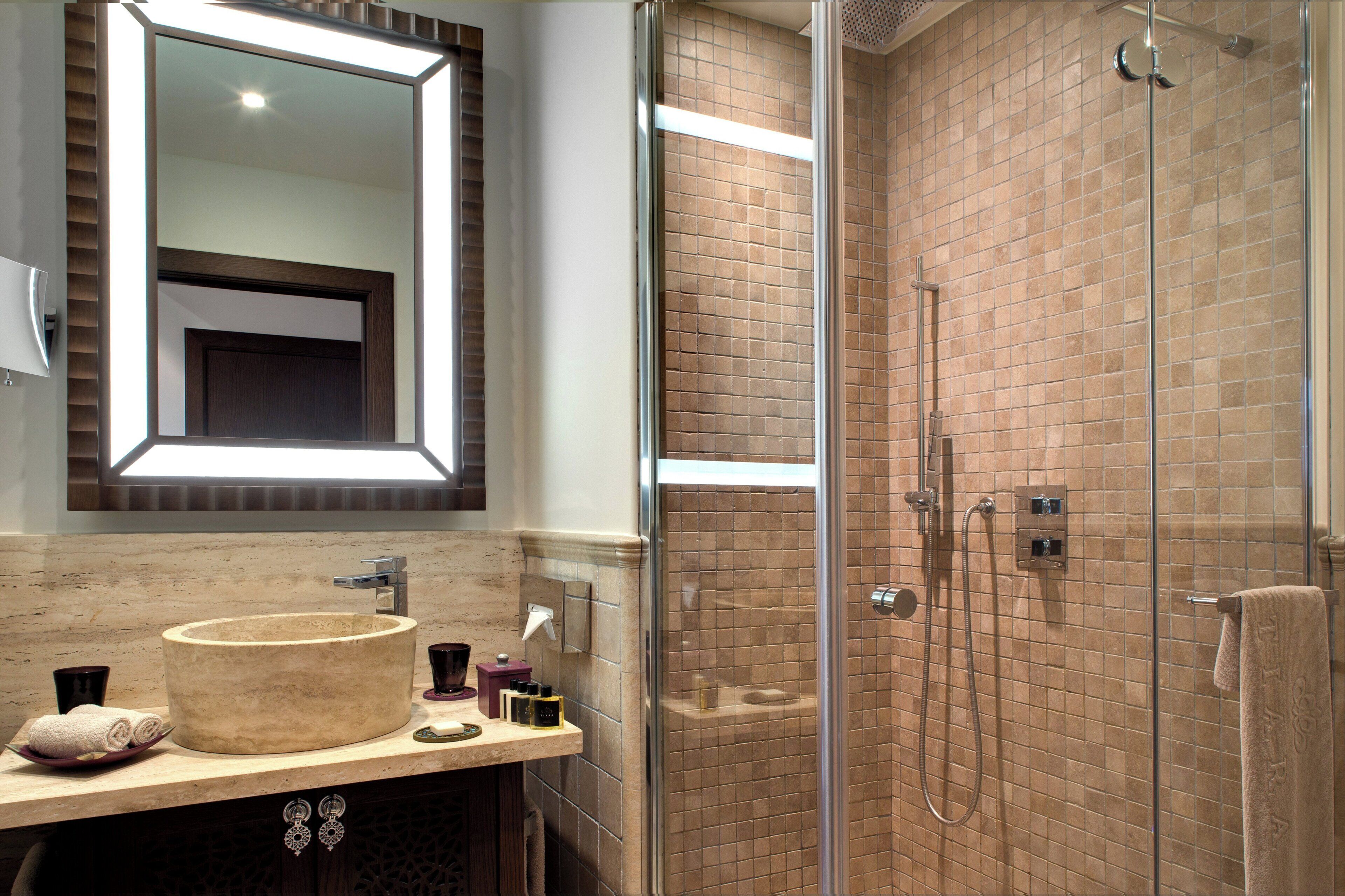 A bathroom with a round sink, a mirror, and a glass-enclosed shower area.