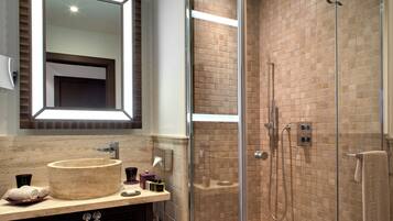 A bathroom with a round sink, a mirror, and a glass-enclosed shower area.