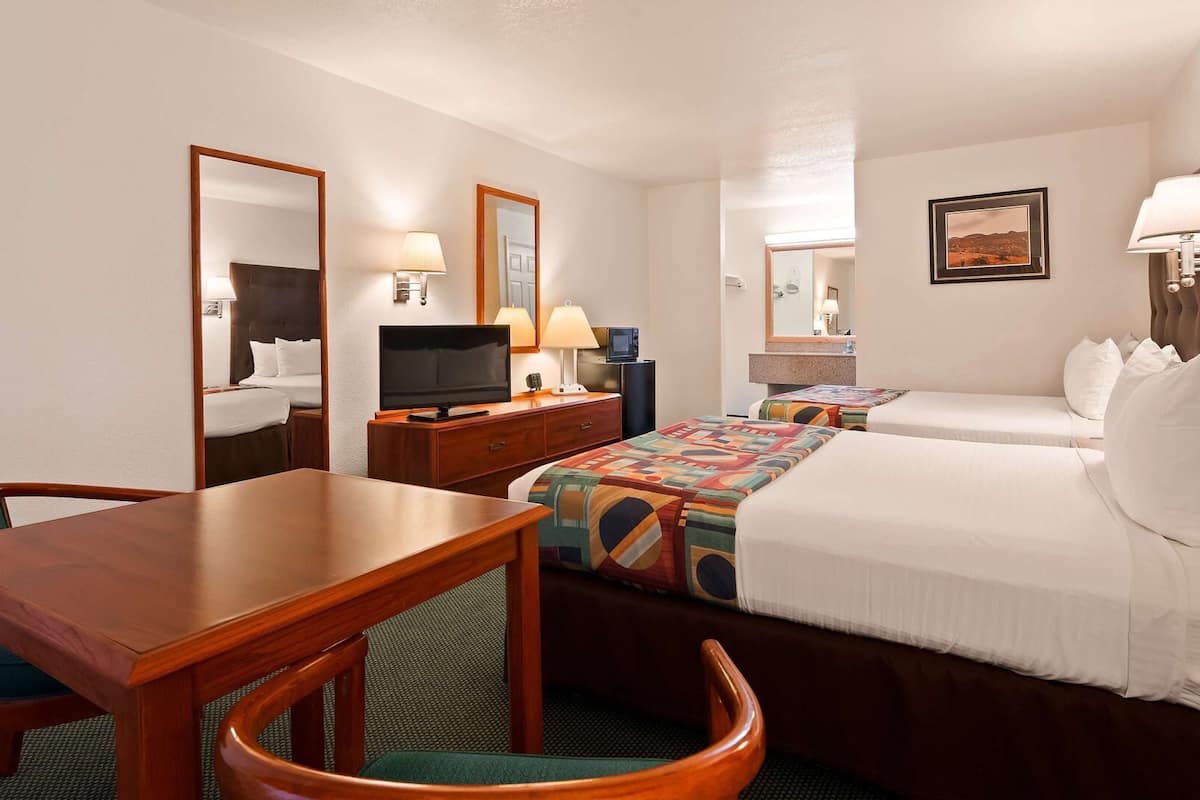 A hotel room with a bed, a desk, a chair, a TV, and a mirror.