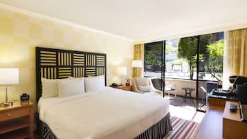 A hotel room with a large bed, a desk, a chair, and a view of the outdoors.
