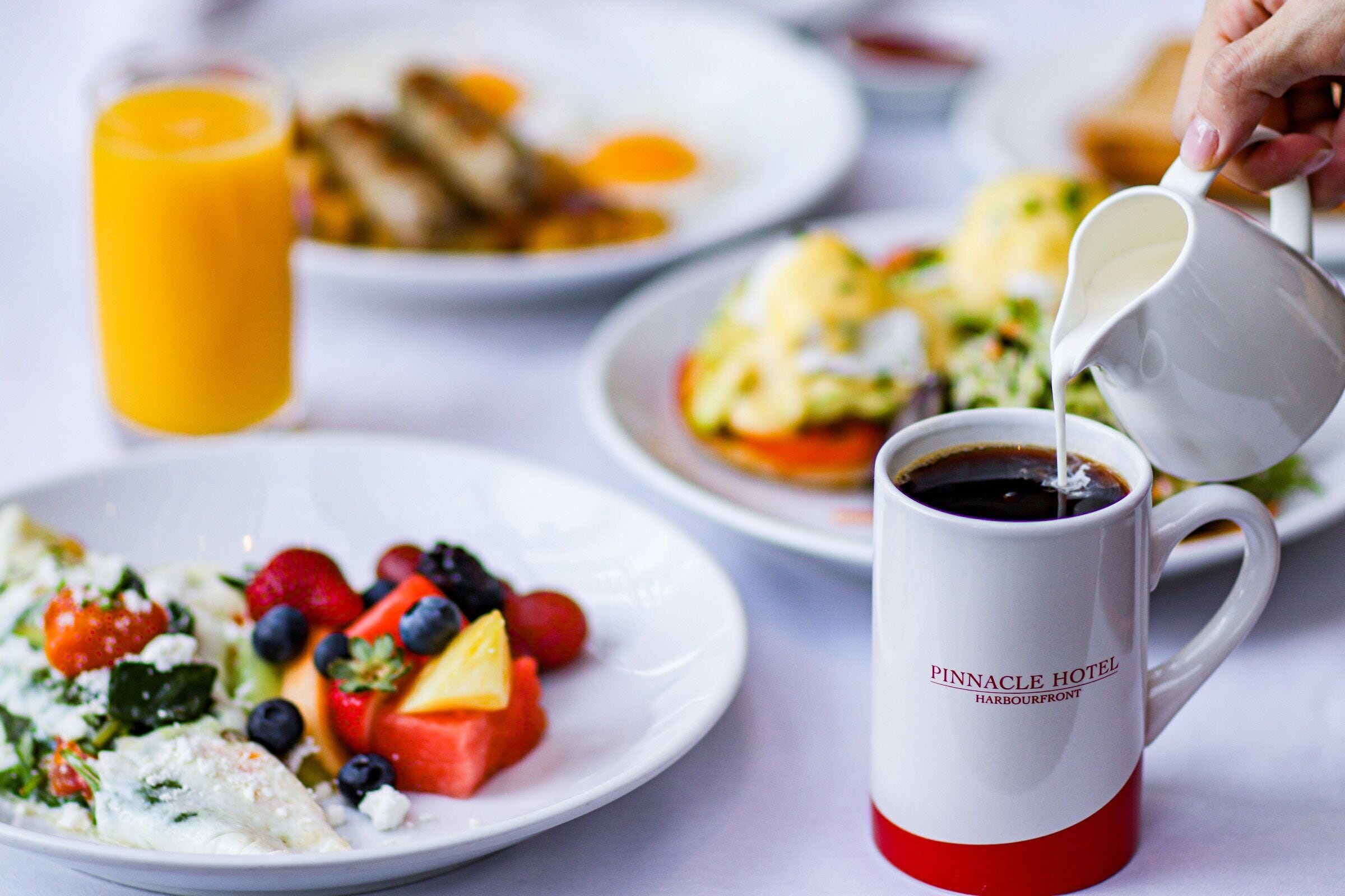 A breakfast setting with plates of food, a glass of orange juice, and a coffee mug.