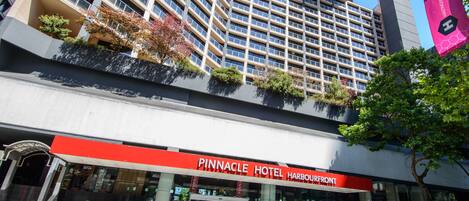 The Pinnacle Hotel Harbourfront with a modern facade, large windows, and a prominent red sign.