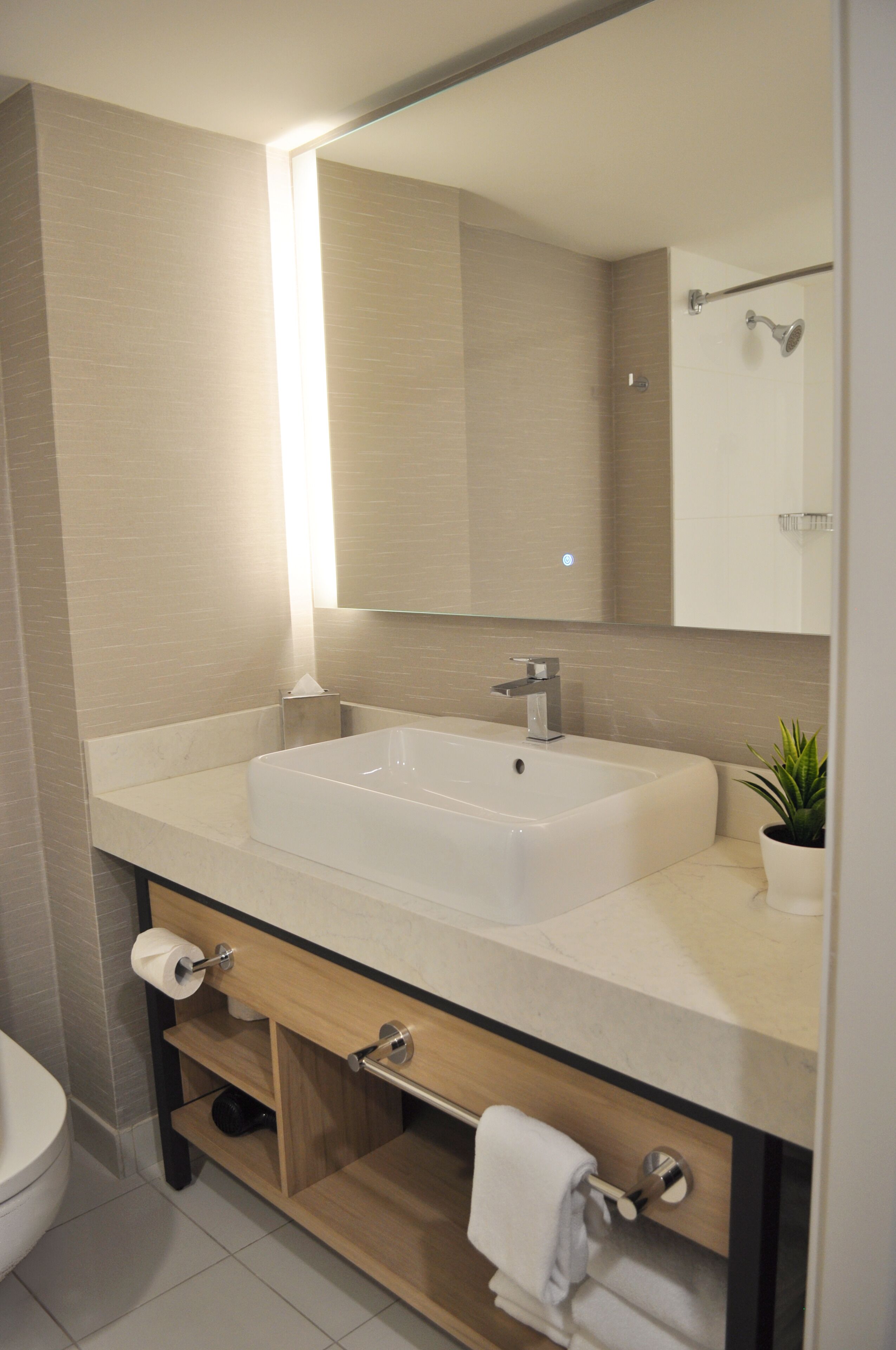 A modern bathroom with a large sink, mirror, and a towel rack.