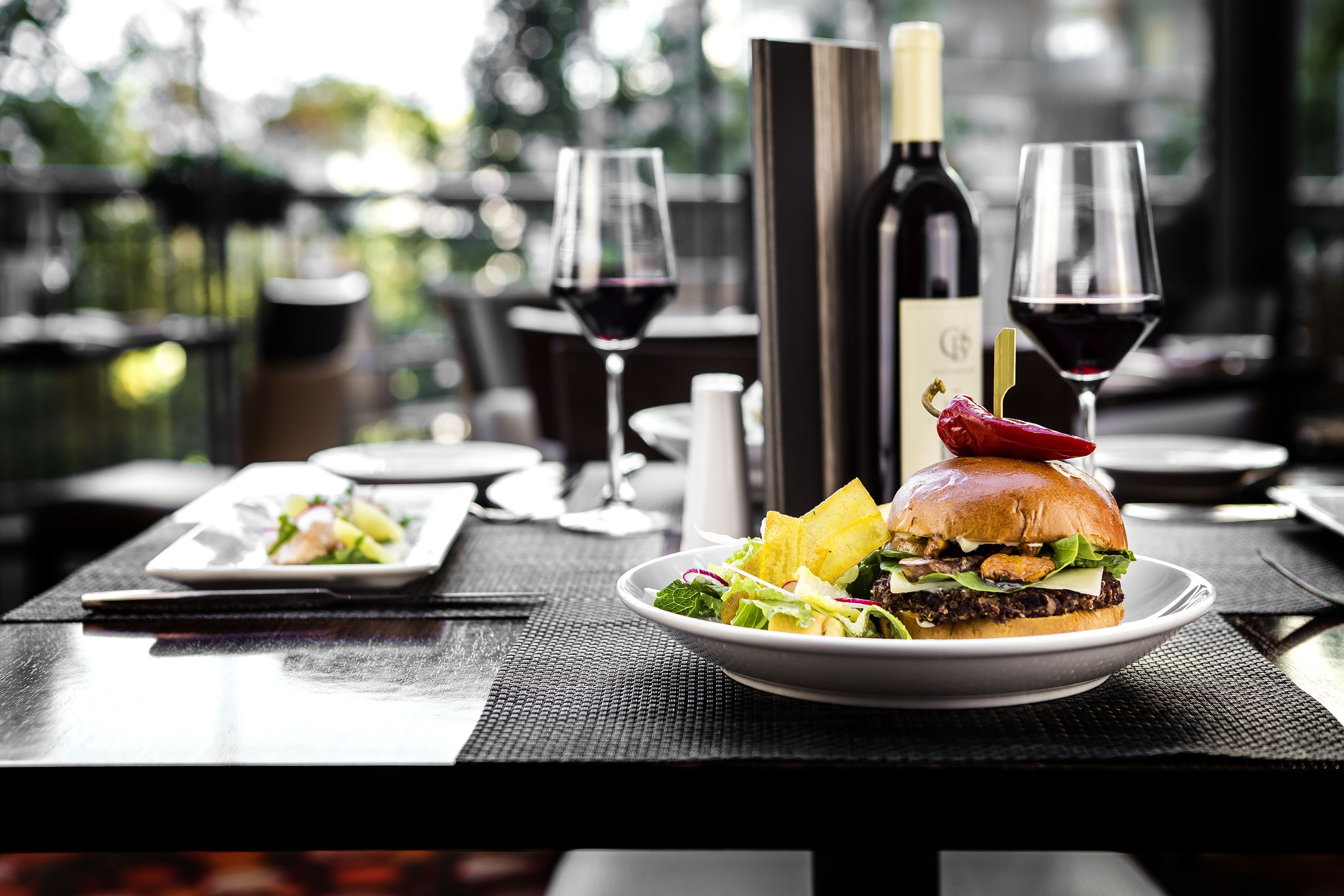 Una mesa de comedor con un plato de comida, una botella de vino y dos copas de vino.