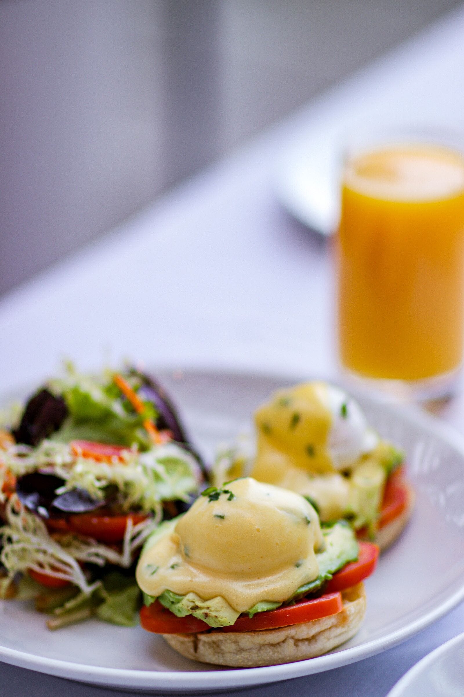 A plate with a sandwich and a glass of orange juice.
