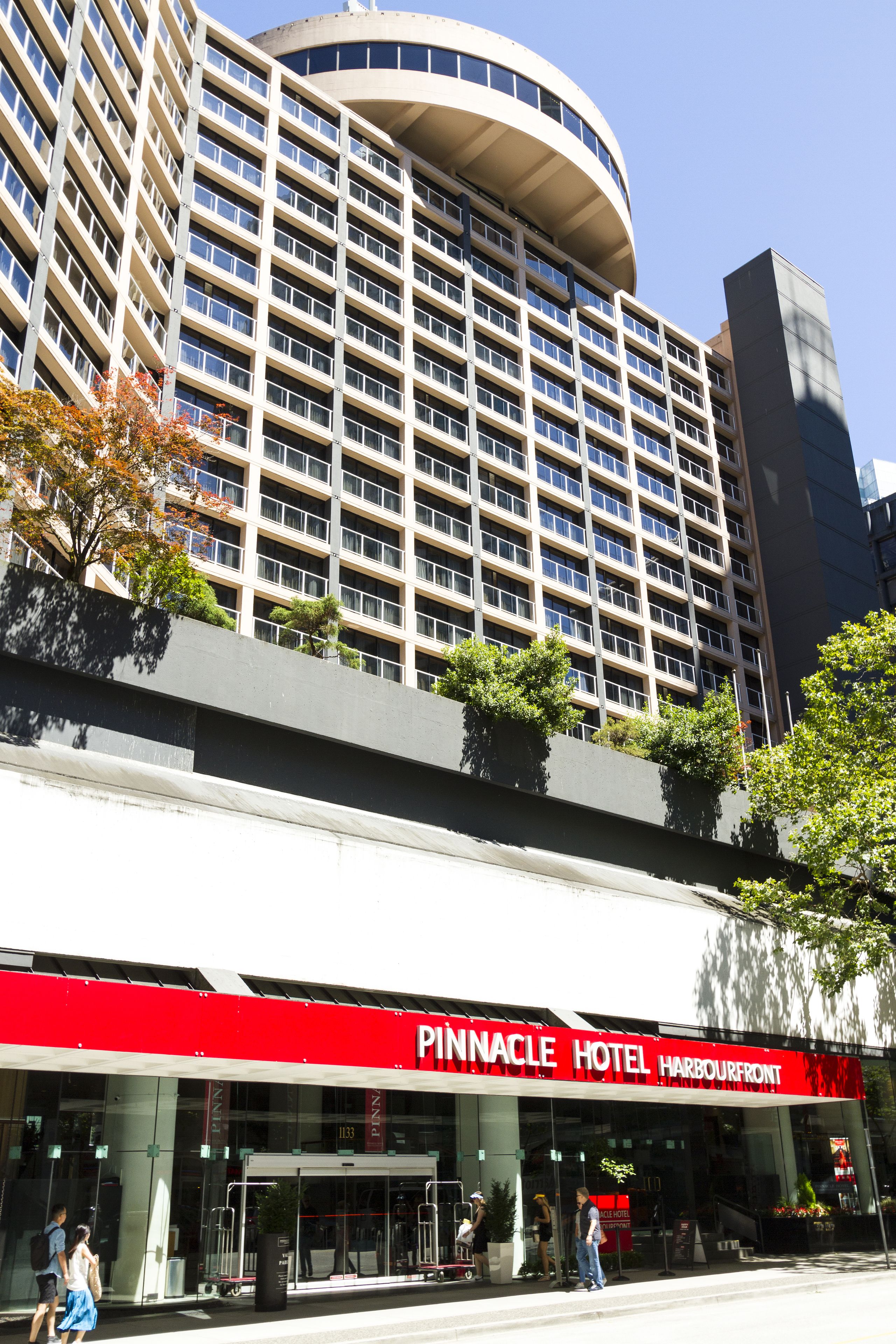 Un hotel de varios pisos con un llamativo letrero rojo y blanco del Pinnacle Hotel Harbourfront.