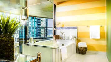 A modern bathroom with a glass shower enclosure, a large bathtub, and a view of a cityscape through the window.