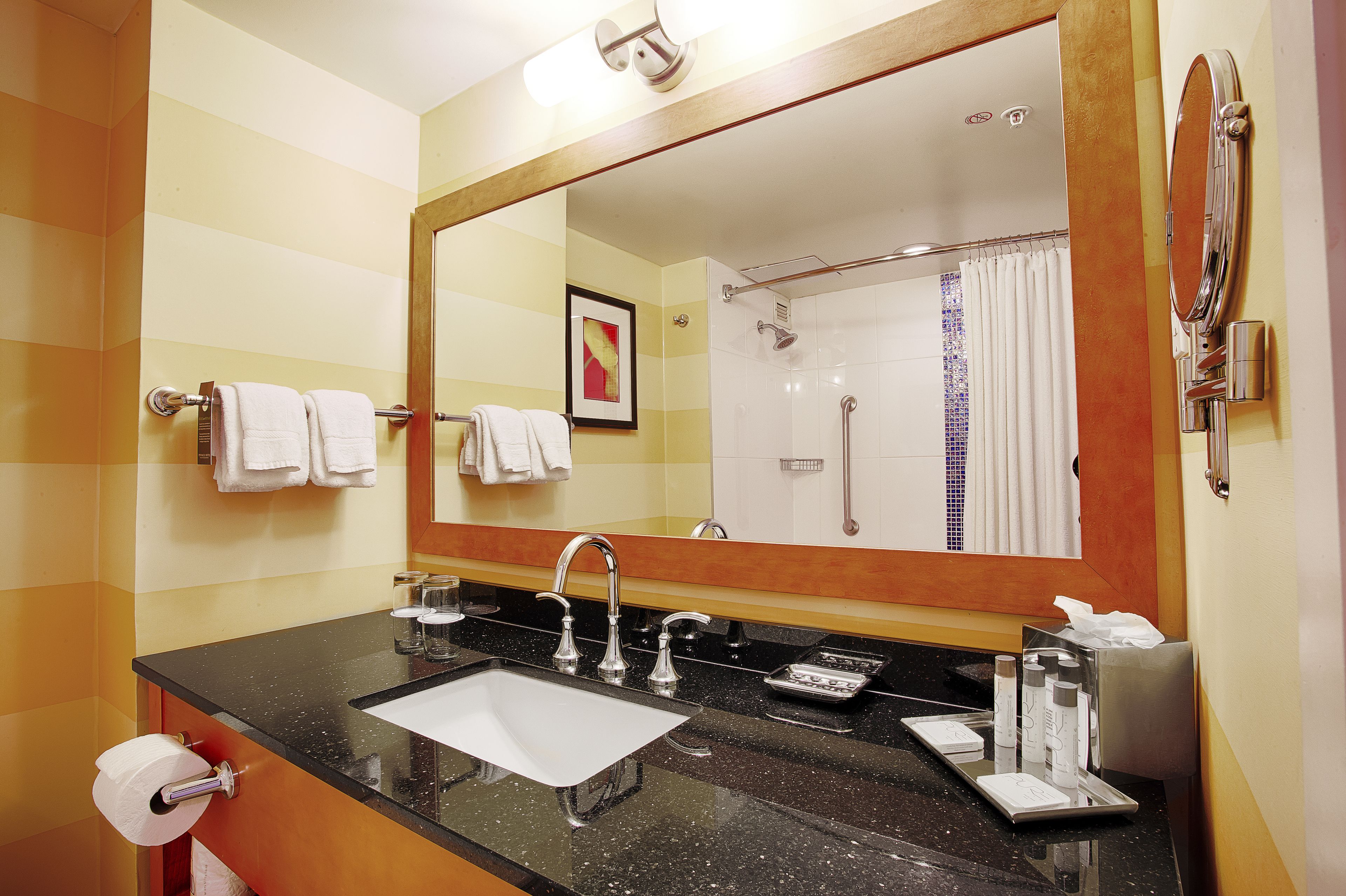 A bathroom with a large mirror, a sink, and a shower.