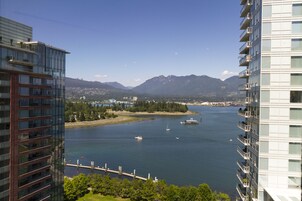 Un edificio alto con vistas a un río tranquilo y montañas a lo lejos.