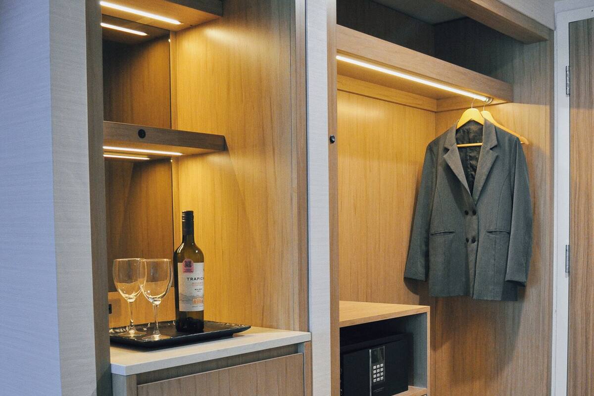 A compact kitchen with a built-in refrigerator, a wine bottle, and glasses on a tray.
