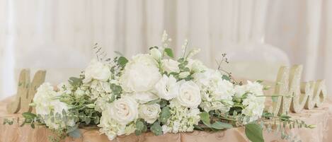 A table with a beige tablecloth and a floral centerpiece.
