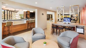 A modern kitchen with a bar area, seating with bar stools, and a television. - DoubleTree by Hilton Pomona (Pomona)