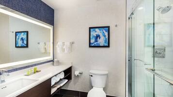 Un bagno moderno con uno specchio grande, un water bianco e box doccia in vetro.