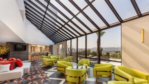 A modern lounge area with green armchairs, a sofa, and a bar area. - DoubleTree by Hilton Pomona (Pomona)