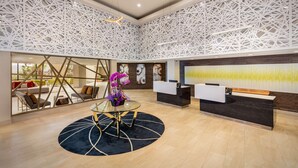 A modern reception area with a glass partition, a reception desk, and a large abstract painting on the wall. - DoubleTree by Hilton Pomona (Pomona)