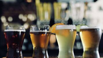 Four glasses of different beverages on a bar counter.