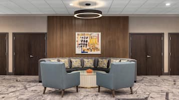 A lobby with a sectional sofa, a round coffee table, and a large abstract painting on the wall.