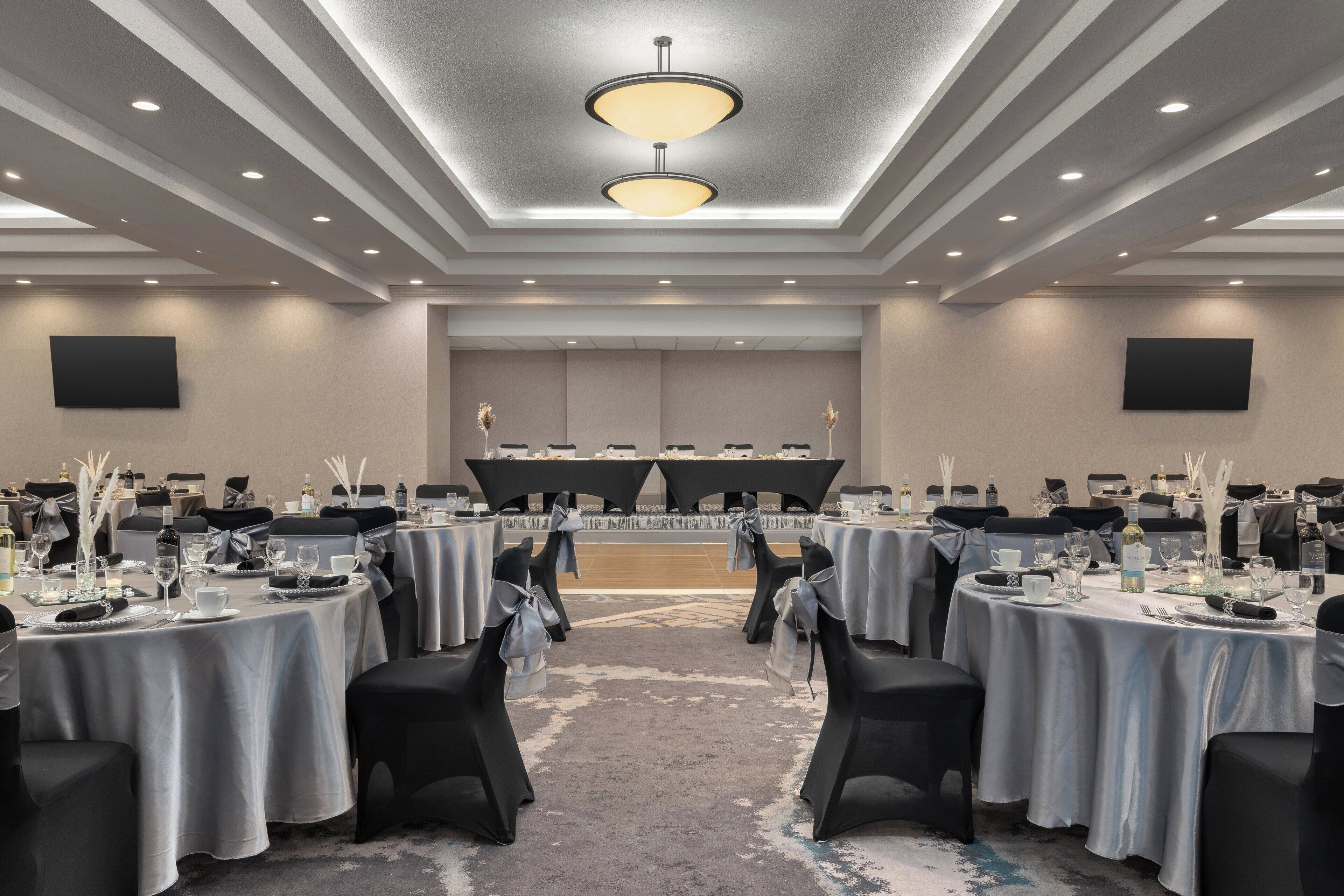 A conference room with round tables, black chairs, and a stage at the front.