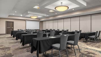 A conference room with multiple tables, chairs, and a projector screen.