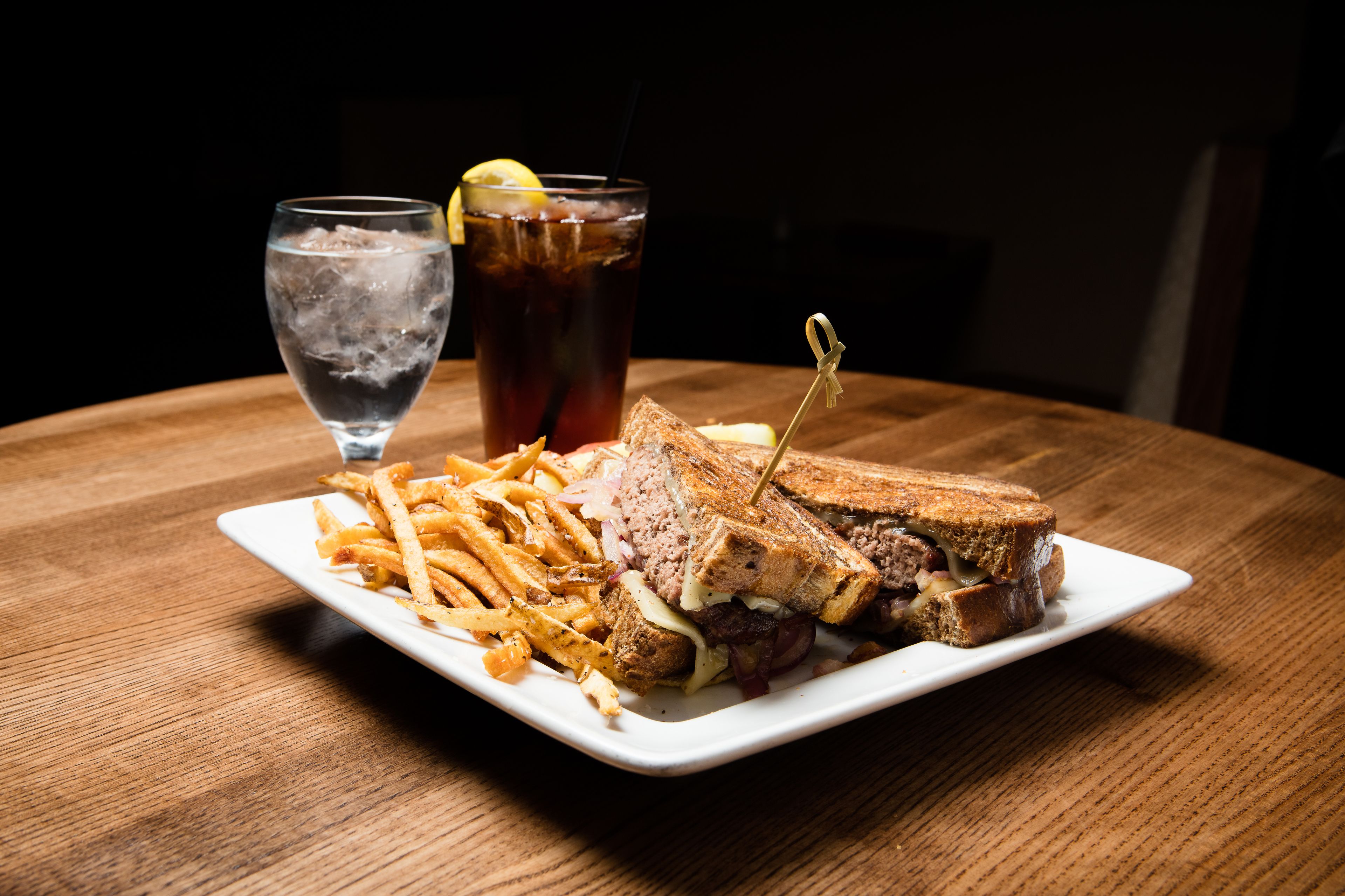 A plate with a sandwich and fries on a wooden table.