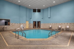 Piscina com chão de azulejos, duas portas e algumas cadeiras ao redor da área da piscina.
