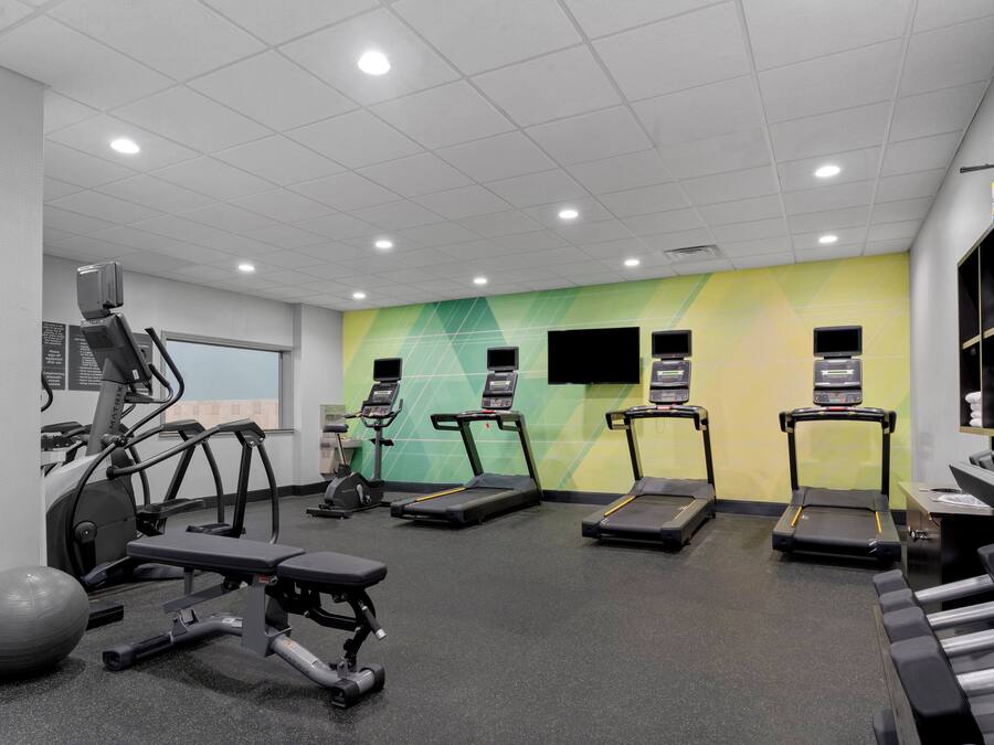 A gym with treadmills, elliptical machines, and free weights.