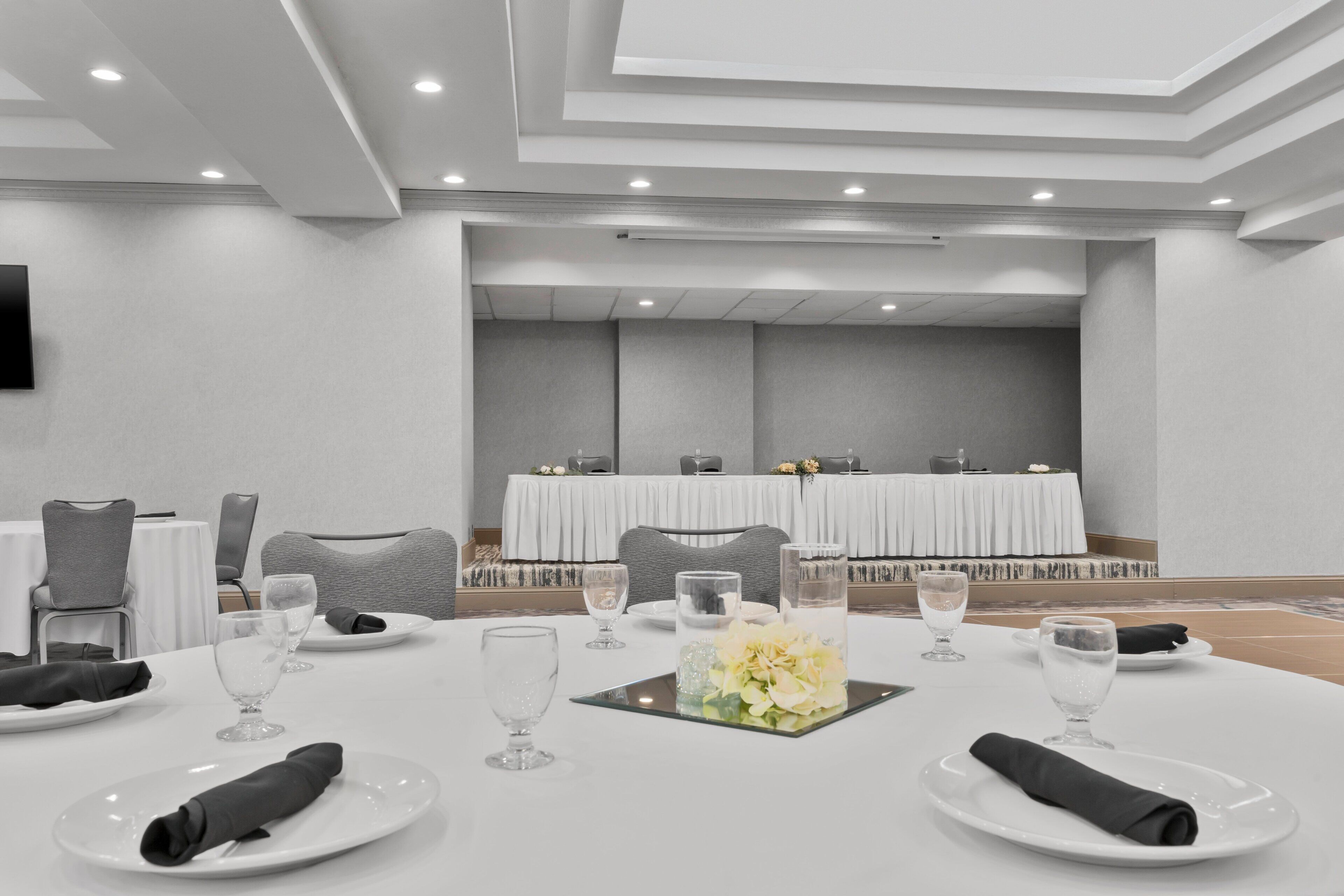 A conference room with a long table set for a meeting, equipped with chairs, plates, glasses, and a centerpiece.