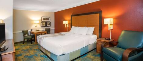 A hotel room with a bed, a desk, a chair, and a TV.