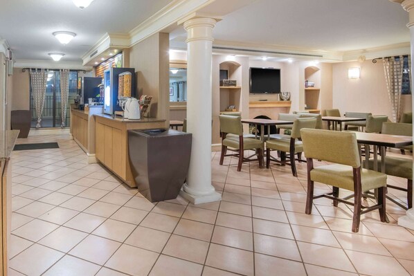 A hotel lobby with a reception desk, seating area, and a television mounted on the wall.