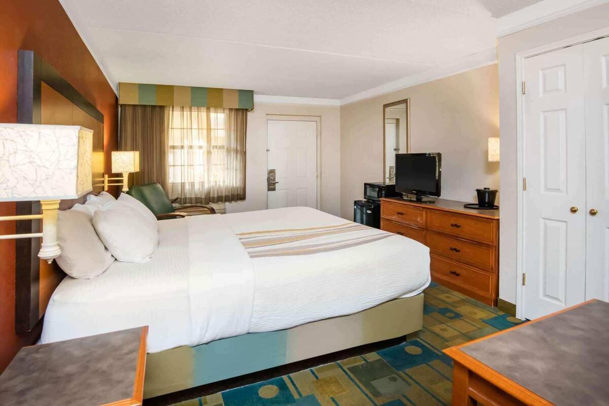 A hotel room with a large bed, a desk, a television, and a wardrobe.