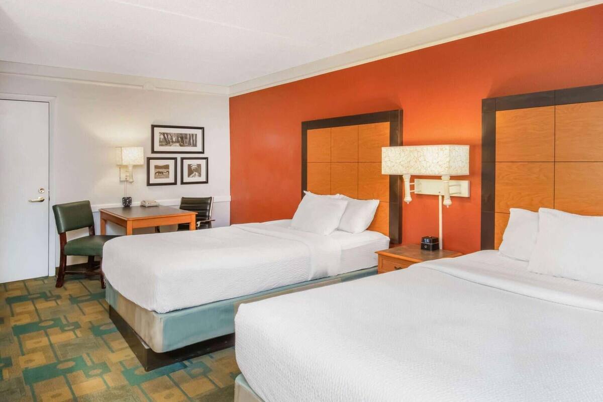 Een hotelkamer met twee bedden, een bureau, een stoel en een lamp.