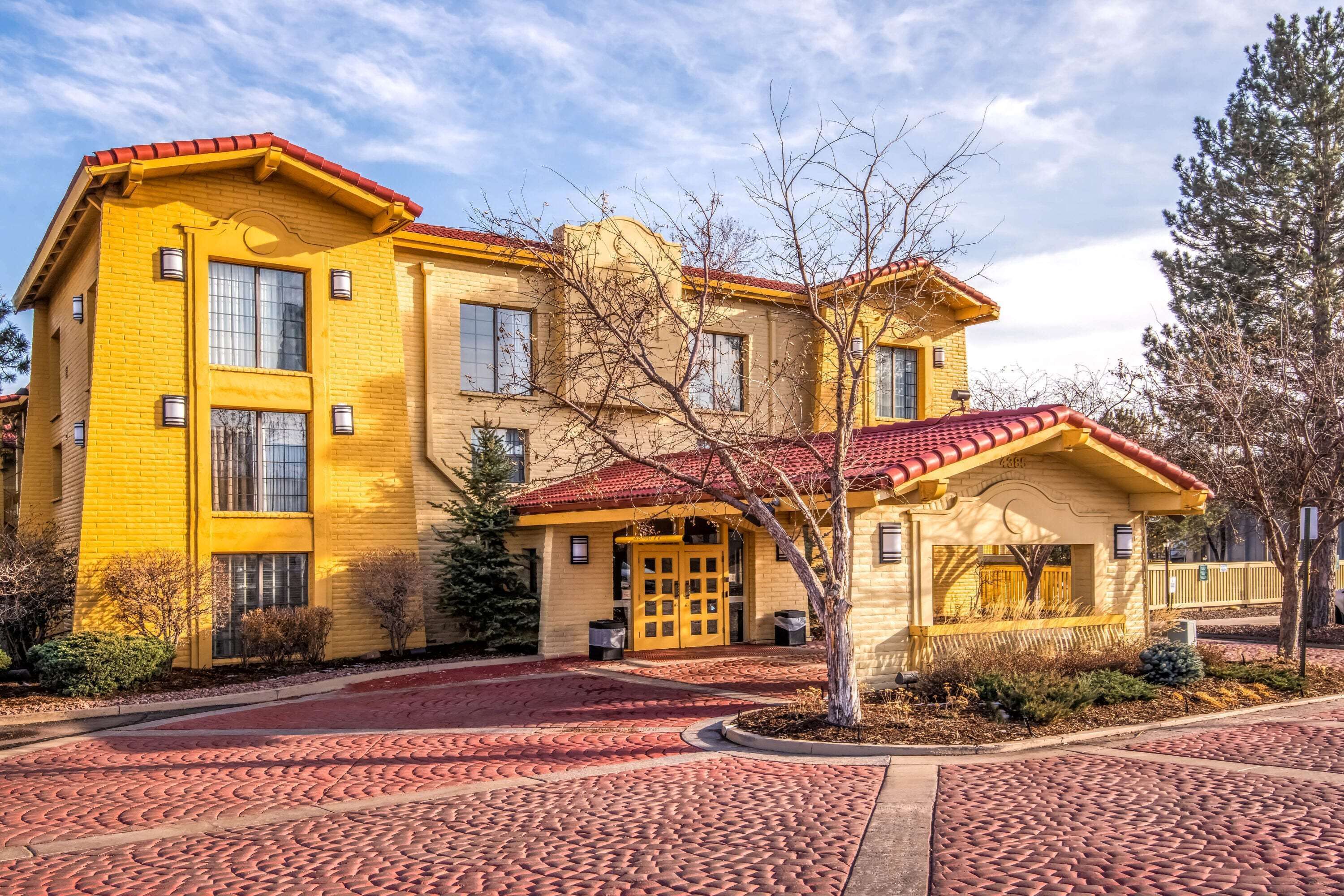 A yellow building with a red-tiled roof, a central entrance, and a small porch.
