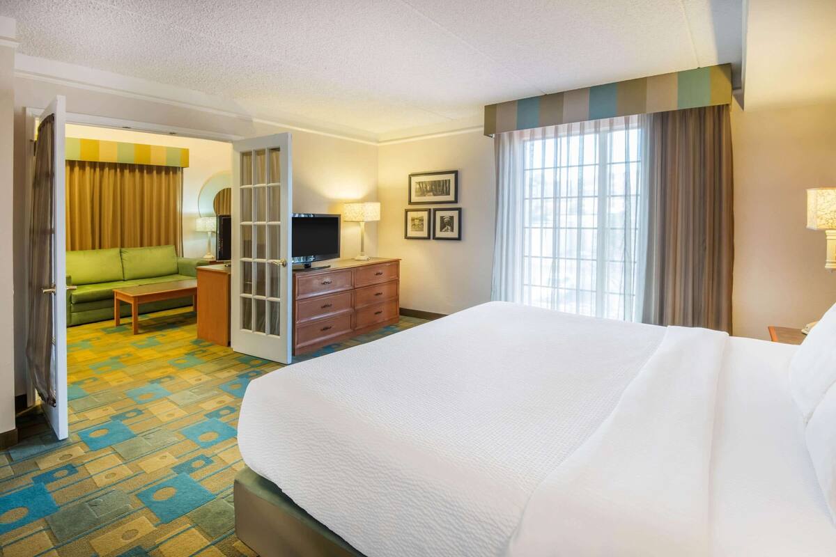 A hotel room with a large bed, a television, a desk, and a green sofa.