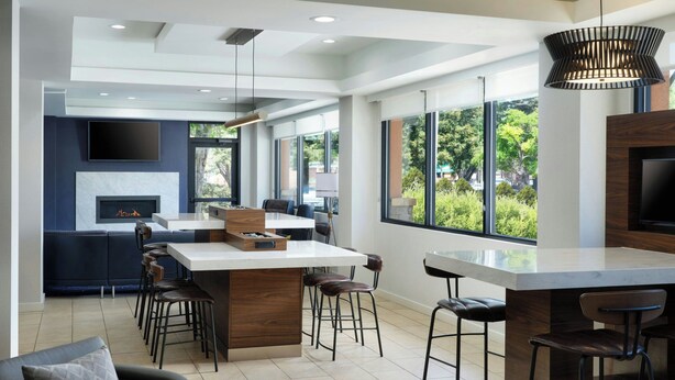 A modern kitchen with a central island, bar stools, and a fireplace. - Courtyard by Marriott Santa Rosa (Santa Rosa)