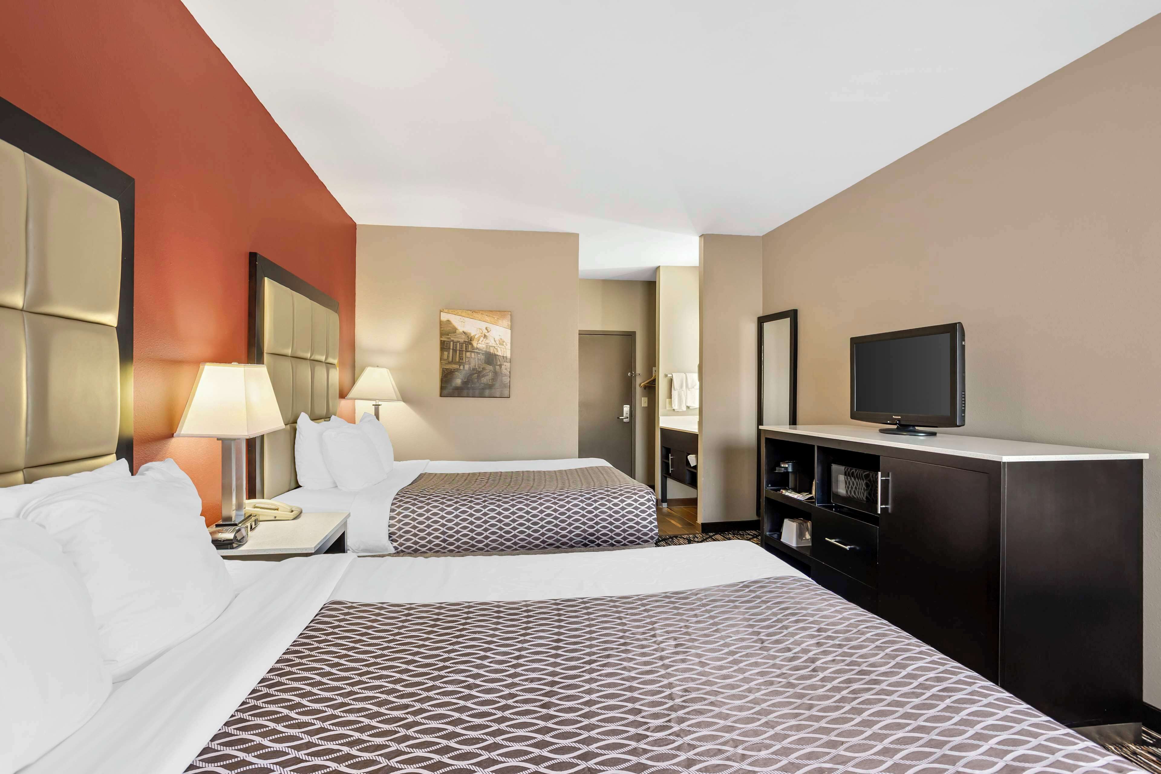 A hotel room with two beds, a TV, a desk with a lamp, and a wardrobe.